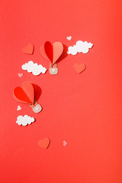 top view of paper heart shaped air balloons in clouds on red background