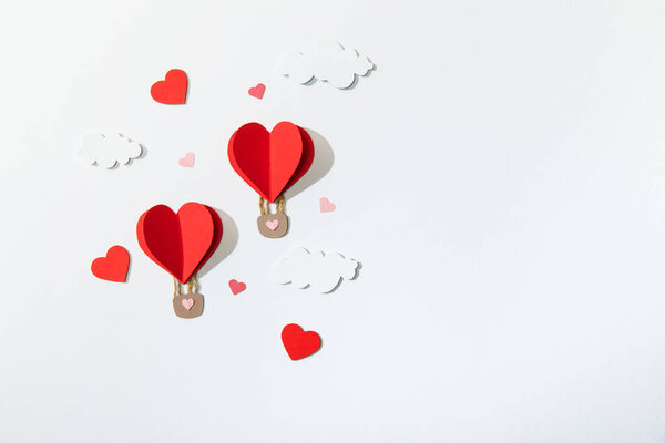 верхний вид бумажных воздушных шаров в форме сердца в облаках на белом фоне
