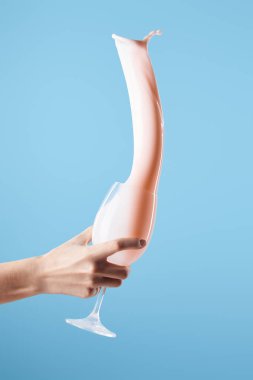 Kırpılmış, elinde bardak tutan, mavi üzerine taze pembe süt sıçratan bir kadın görüntüsü.