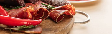delicious meat platters served with rosemary and chili pepper on wooden board on beige background, panoramic shot clipart