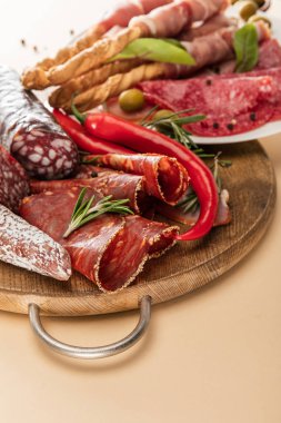 Zeytin, baharat ve ekmek çubuklarıyla servis edilen lezzetli et tabakları ve bej arka planda ahşap tahta tabaklar.