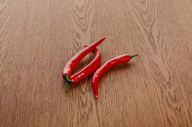 red spicy chili peppers on wooden brown table clipart