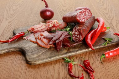 delicious meat platter served with chili pepper and rosemary on wooden table clipart