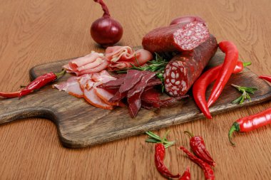 delicious meat platter served with chili pepper and rosemary on wooden table clipart