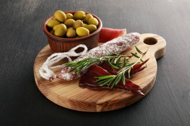 Siyah yüzeyde zeytinlerle servis edilen lezzetli et tabağı.