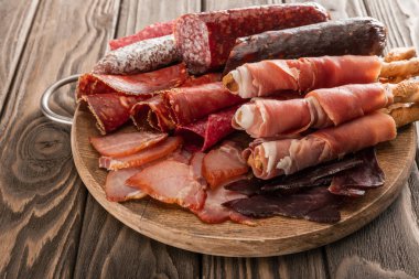 Tahtada ekmek çubuklarıyla servis edilen lezzetli et tabağının üst görüntüsü.