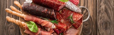top view of delicious meat platter served with rosemary and breadsticks on wooden board, panoramic shot clipart