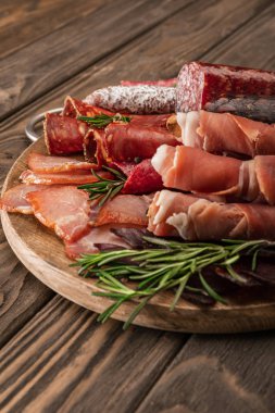 delicious meat platter served with rosemary on wooden board clipart