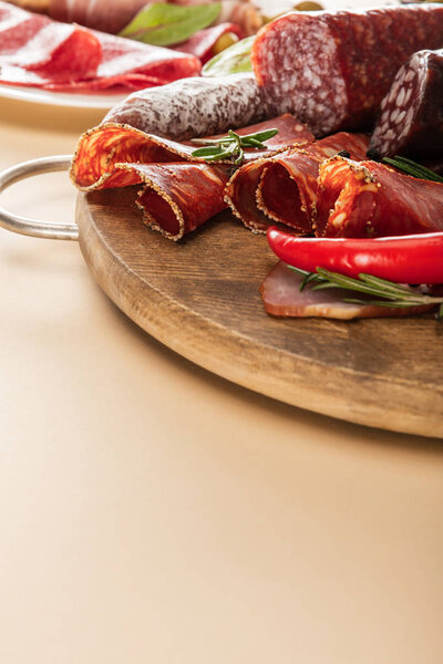 delicious meat platters served with rosemary and chili pepper on wooden board on beige background