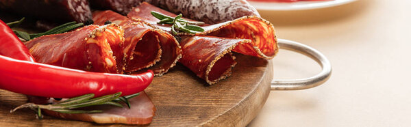 delicious meat platters served with rosemary and chili pepper on wooden board on beige background, panoramic shot