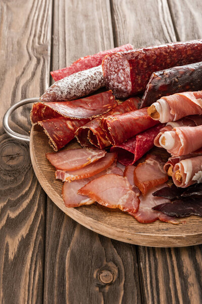 top view of delicious meat platter served with breadsticks on wooden board