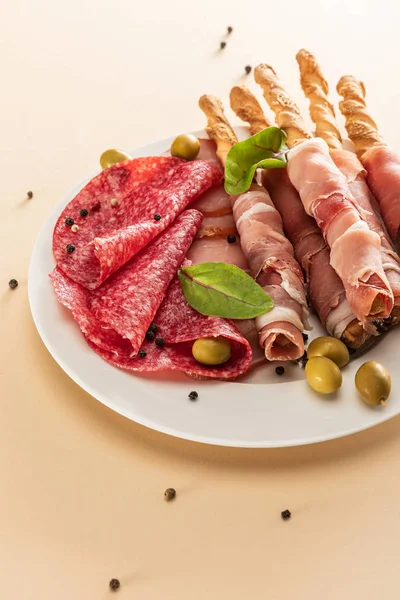 Delicious Meat Platter Served Olives Breadsticks Plate Beige Background — Stock Photo, Image