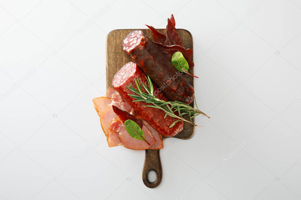 top view of delicious meat platter served with rosemary on wooden board isolated on white