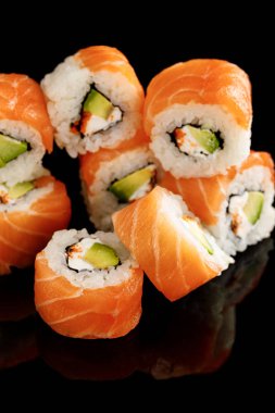 delicious Philadelphia sushi with avocado, creamy cheese, salmon and masago caviar isolated on black clipart