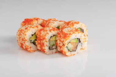 Beyaz yüzeyde avokado, somon ve masago havyarlı nefis California dürümü.