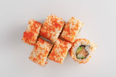 Avokado, somon ve masago havyarlı nefis California Roll 'un beyaz yüzeyi.