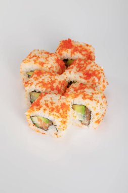 Beyaz yüzeyde avokado, somon ve masago havyarlı nefis California dürümü.