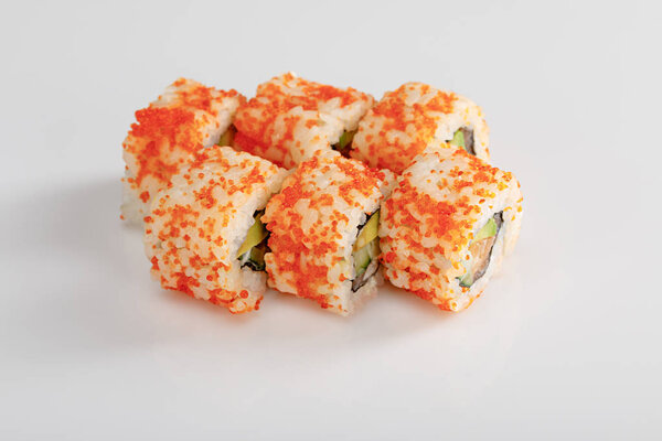 delicious California roll with avocado, salmon and masago caviar on white surface