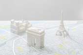 selektivní zaměření malých figurek na mapě Paříže izolované na šedé  