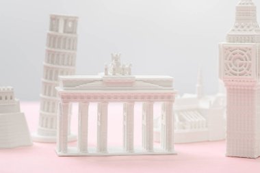 selective focus of brandenburg gate figurine near big ben tower statuette on grey and pink  clipart