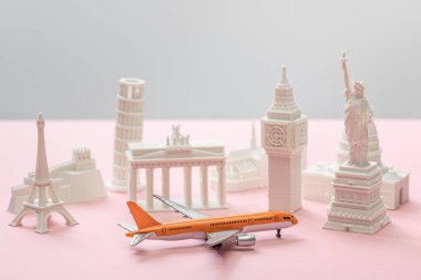 Gri ve pembe üzerinde farklı ülkelerin küçük heykelciklerinin yanında oyuncak uçak 