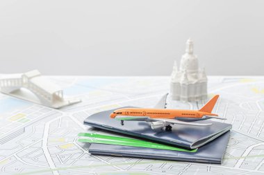 Pasaportların yanındaki oyuncak uçağın seçici odak noktası ve gri üzerinde izole edilmiş İtalya haritasındaki küçük heykelcikler  