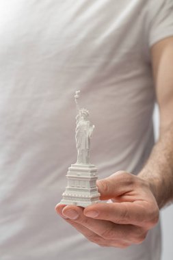 cropped view of man holding small statue of liberty  clipart