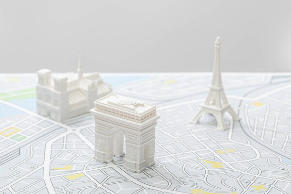 selective focus of small figurines on map of paris isolated on grey  