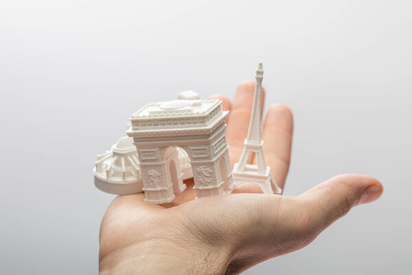 cropped view of man holding small souvenirs from paris isolated on grey 