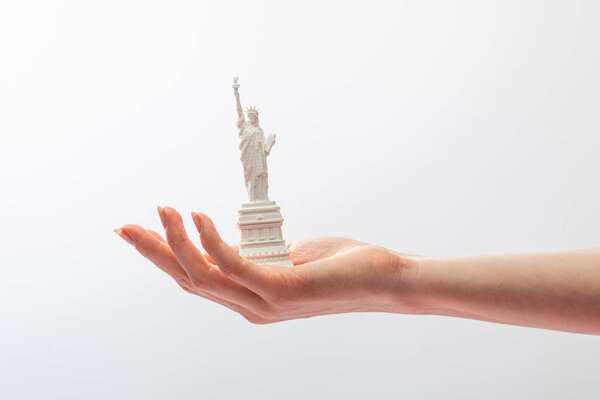 обрезанный вид женщины, держащей маленькую статую свободы, изолированную на белом
 