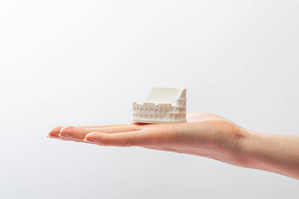 cropped view of girl holding small statuette of colosseum isolated on white 