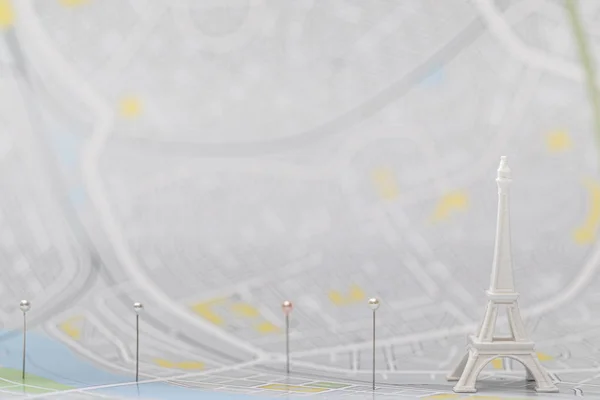 パリ地図上の小さなエッフェル塔フィギュア付近のピンの選択的焦点 — ストック写真