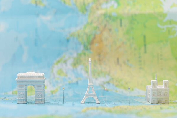 small figurines with city attractions on map of paris with pins 