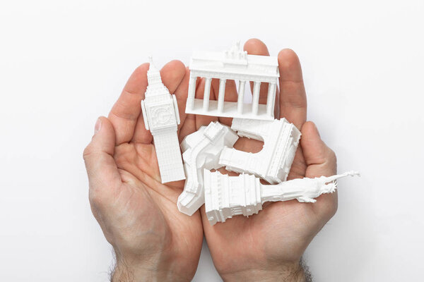 top view of man holding small figurines with attractions in hands isolated on white 