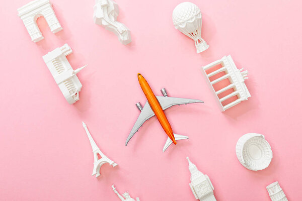 top view of figurines from countries near toy plane on pink 