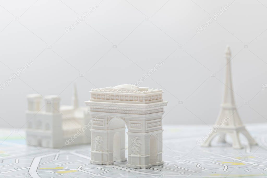 selective focus of arc de triomphe near small figurines on map of paris isolated on grey  