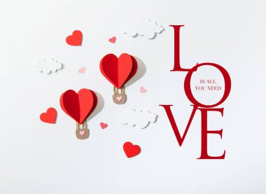 top view of paper heart shaped air balloons in clouds near love is all you need lettering on white background clipart