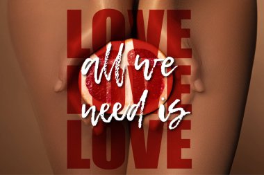 cropped view of woman in nylon tights holding grapefruit half near all we need is love lettering on brown clipart