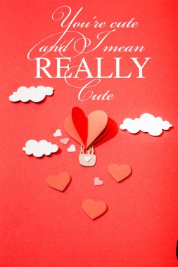 top view of paper heart shaped air balloon in clouds near you're cute and i mean really cute lettering on red background clipart