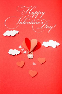 top view of paper heart shaped air balloon in clouds near happy valentines day lettering on red background clipart