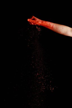 Siyah zemin üzerinde kırmızı renkli holi boya tozu olan kadın eli