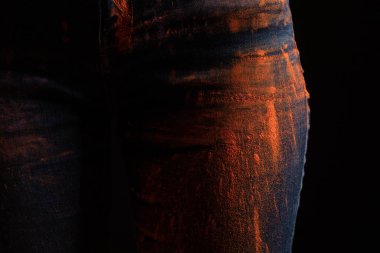 Kırpılmış turuncu renkli holi boyalı kadın manzarası siyah üzerine izole edilmiş kot pantolon.