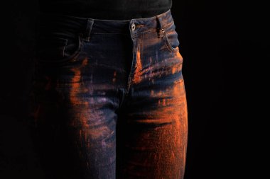 Kırpılmış turuncu renkli holi boyalı kadın manzarası siyah üzerine izole edilmiş kot pantolon.
