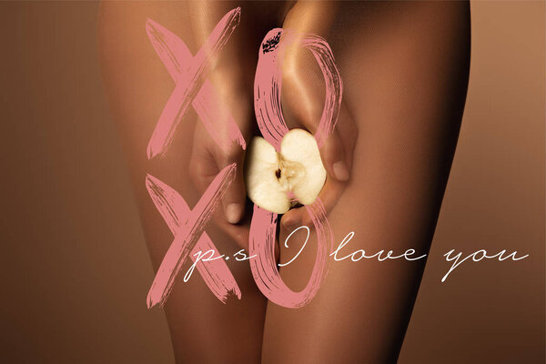 cropped view of woman in nylon tights holding apple half near ps i love you lettering on brown
