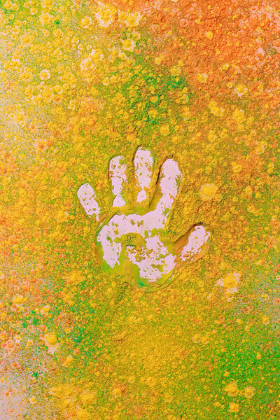 handprint on orange, yellow and green colorful holi paint explosion