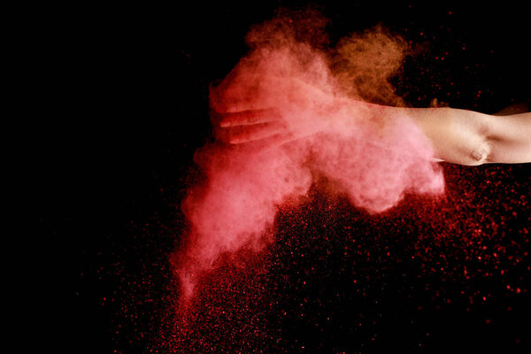 женская рука в розовых красочных Holi краски взрыв на черном фоне
