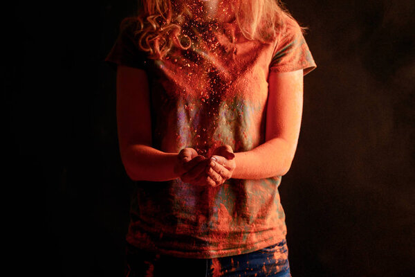 обрезанный вид женщины с оранжевым красочным Holi порошок краски изолированы на черном
