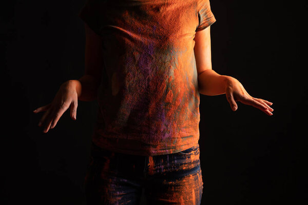 обрезанный вид женщины с оранжевым красочным Holi краски порошок на теле и одежда изолированы на черном
