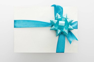 Mavi dekoratif saten kurdeleli boş kartın üst görünümü ve beyaz arkaplanda yay