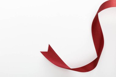Saten bordo dekoratif kıvrımlı kurdelenin beyaz üzerine izole edilmiş üst görünümü